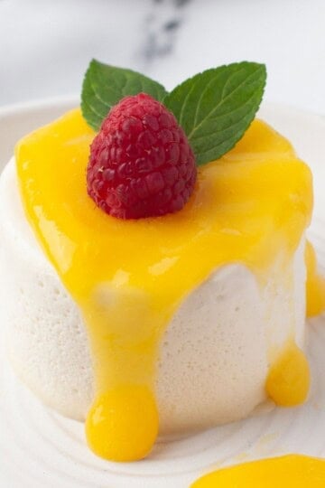 panna cotta with mango sauce and garnished with a raspberry and two mint leaves