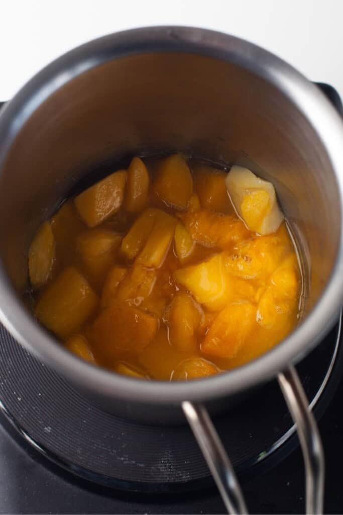 Mango sauce simmering in a saucepan with sugar and lemon juice