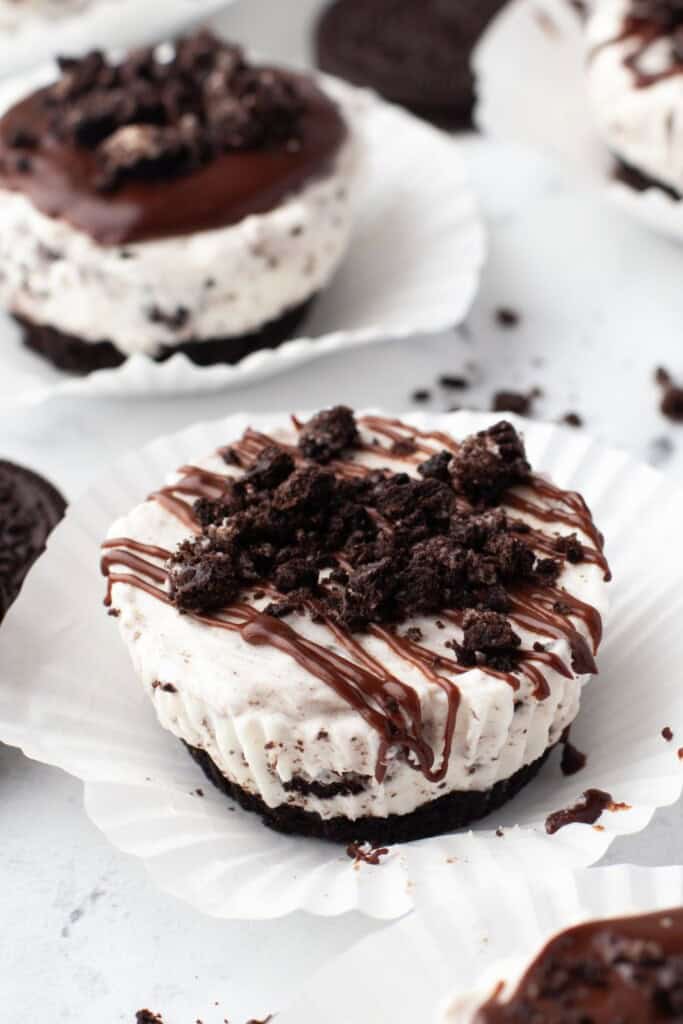 No bake mini Oreo cheesecakes topped with chocolate ganache drizzle and crushed Oreos