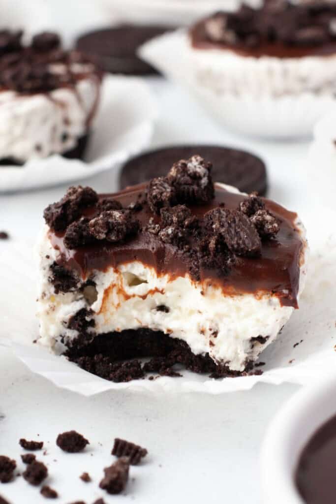 Bite taken from a no bake Oreo cheesecake showing the crust, filling, and ganache layers