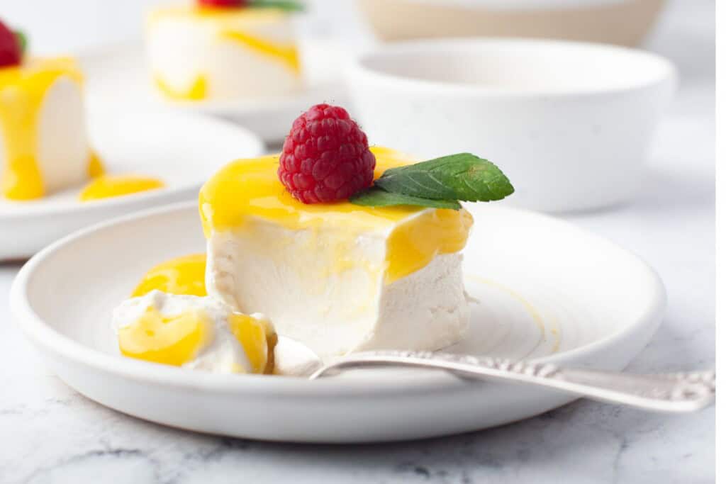 Spoonful taken from a creamy vanilla panna cotta showing its silky texture under mango sauce