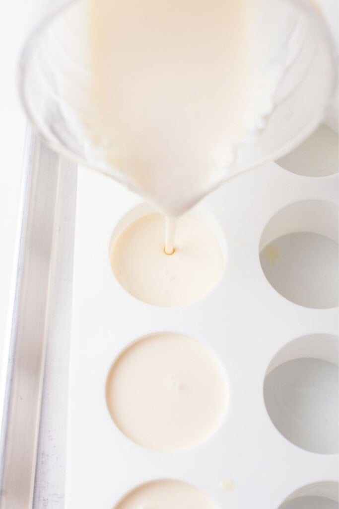 Pouring vanilla panna cotta mixture into greased silicone molds