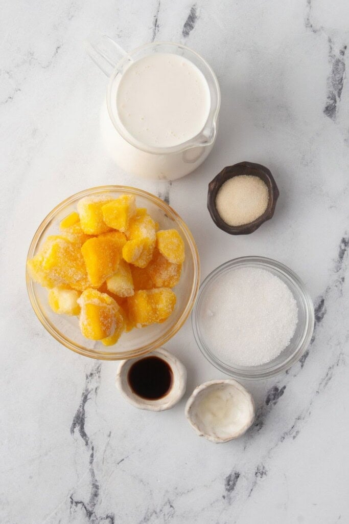 Ingredients for panna cotta with mango sauce including heavy cream, gelatin, sugar, vanilla, and frozen mango
