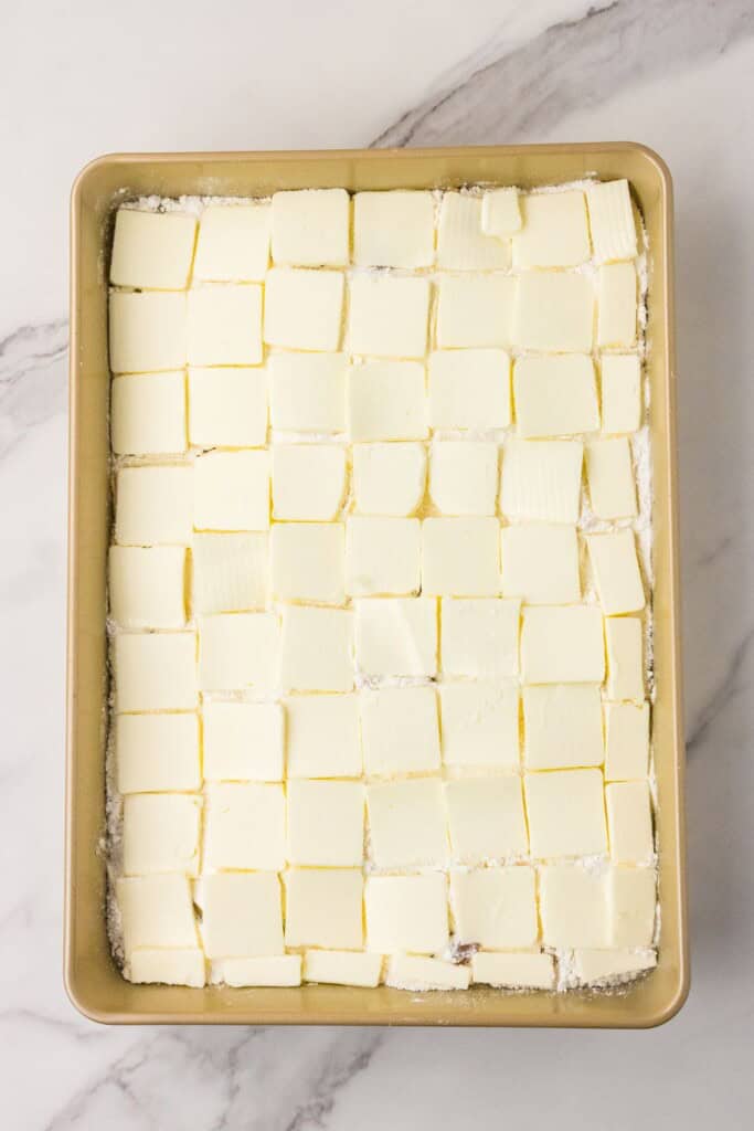 full cup of butter slices covering peach dump cake before baking