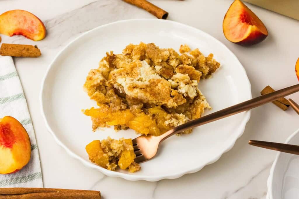 warm peach dump cake serving with melting vanilla ice cream