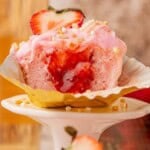 Cross-section of pink champagne cupcake showing strawberry filling center