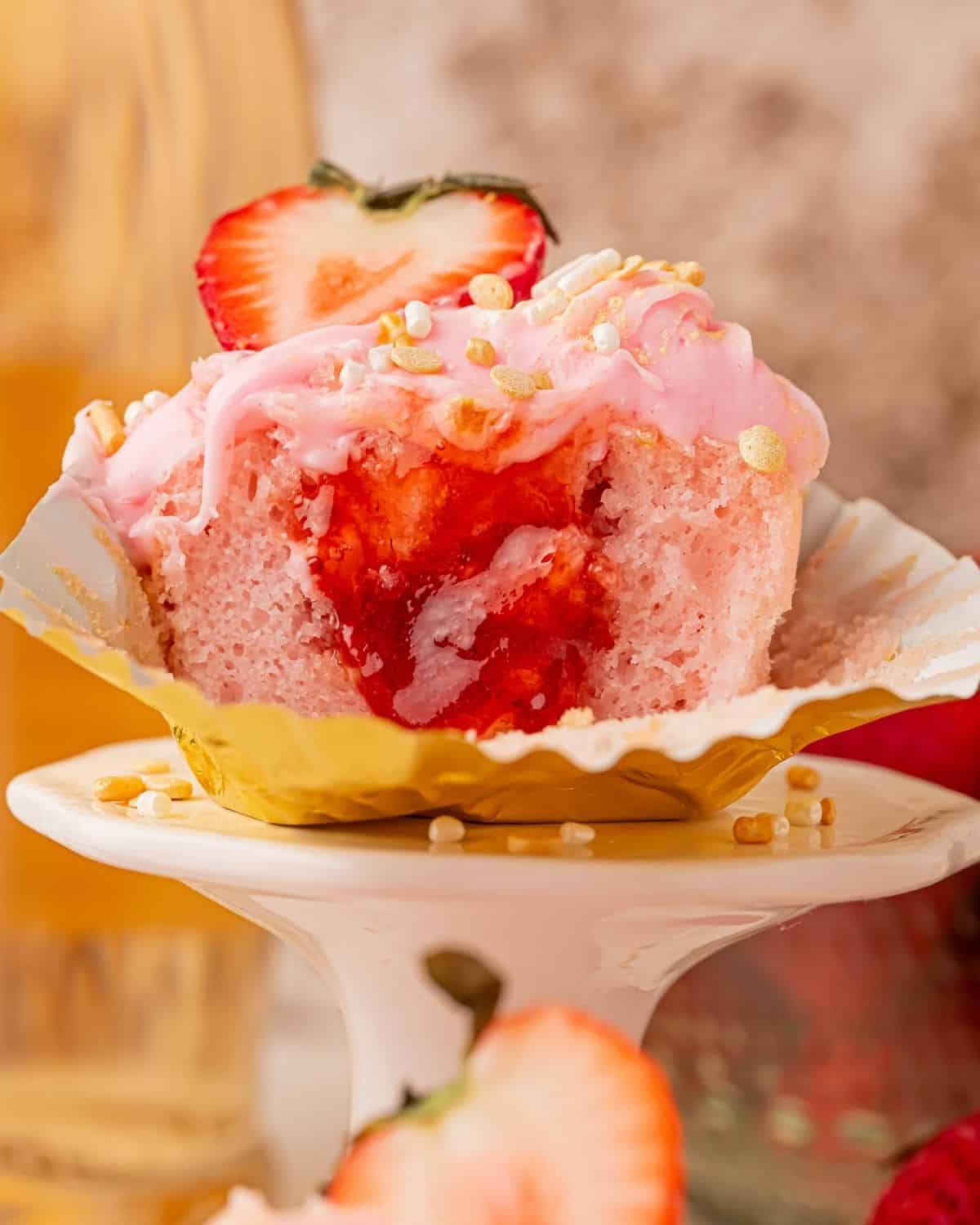 Cross-section of pink champagne cupcake showing strawberry filling center
