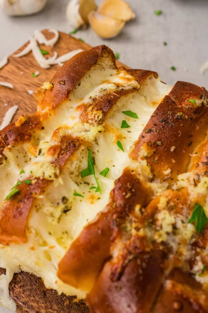 Close up of golden Hawaiian roll garlic bread with melted mozzarella and fresh parsley