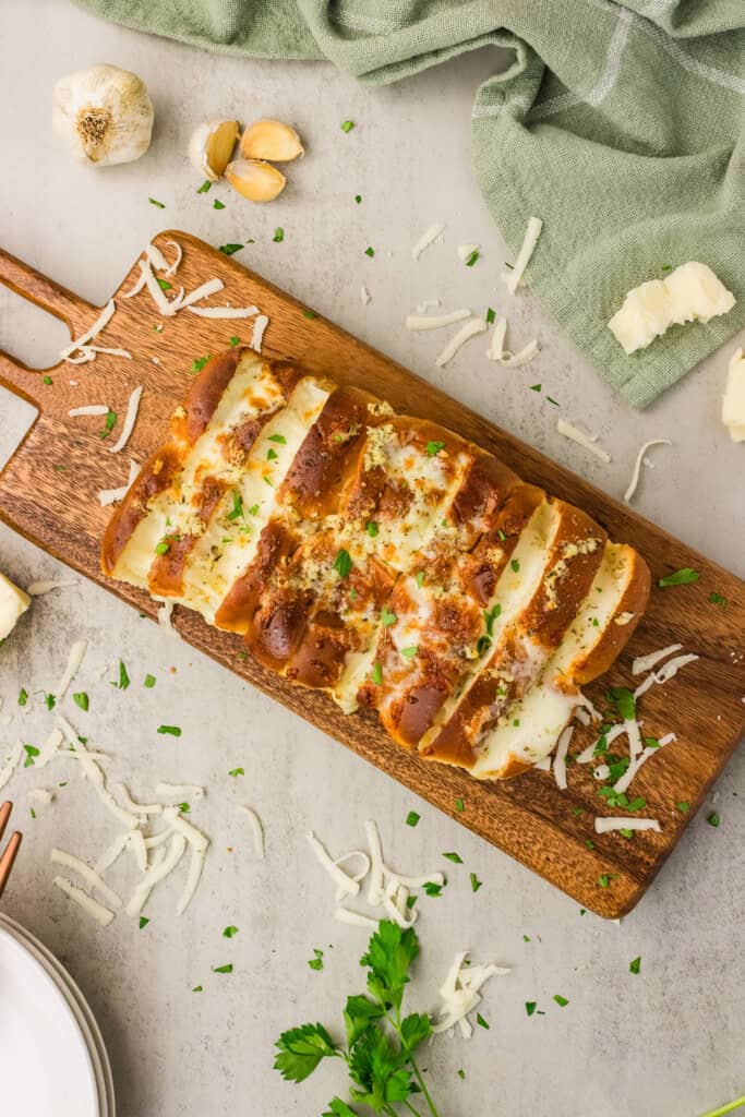 Overhead view of cheesy Hawaiian roll garlic bread on a wooden serving board