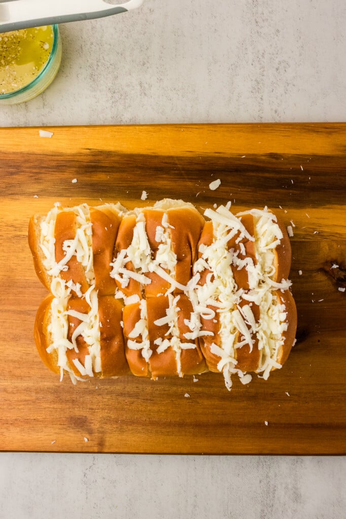 Shredded mozzarella stuffed into the cuts of connected Hawaiian rolls