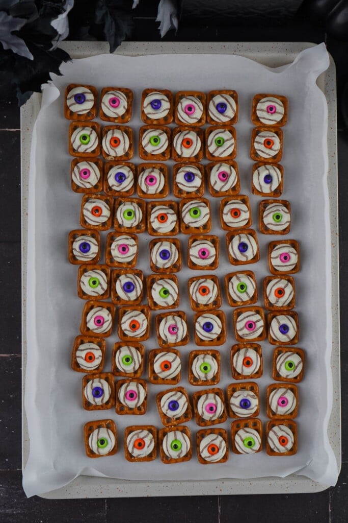 Full baking sheet of sixty finished eyeball pretzel bites cooling on parchment